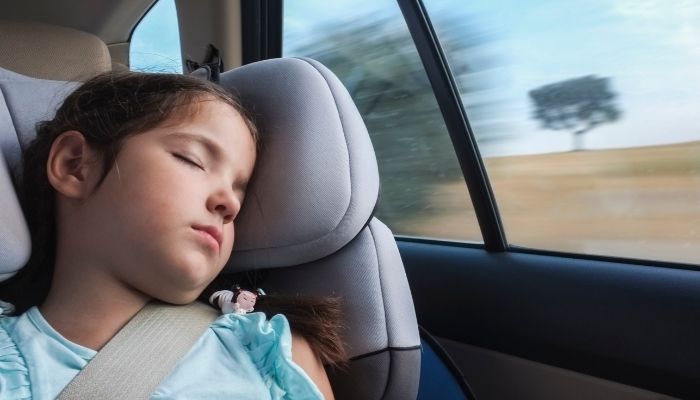 A child asleep in a child seat in a car