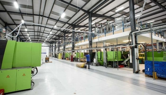 The interior of a high-volume plastic injection moulding facility with multiple green injection moulding machines