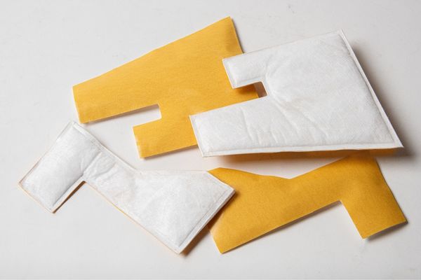 Pieces of white 3M Thinsulate fabric insulation cut, sealed and bonded with adhesive tape