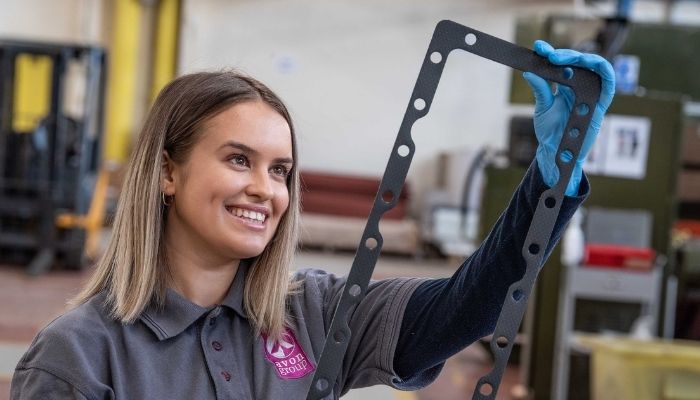 A woman checks the quality and finish of a large rectangular gasket in an Avon Group factory