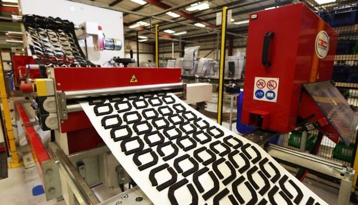 A red kiss cutting machine making black foam gaskets at an Avon Group factory