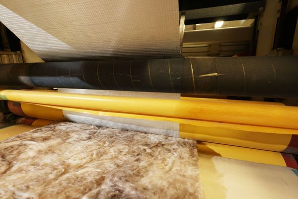 A machine laminating metal foil onto fleece insulation for use in commercial catering equipment